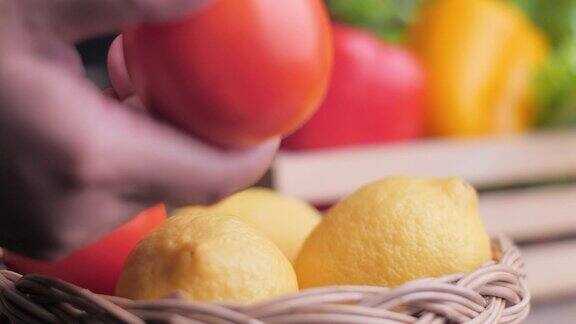 在柳条篮子里挑选蔬菜特写手拿起一个柠檬和一个番茄