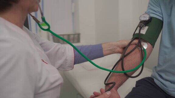 女医生在诊所体检时用血压计给男病人测量血压心脏病专家在心脏病医院检查男性患者的血压