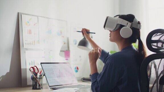TheMetaverse:亚洲女性戴着VR眼镜在办公室工作