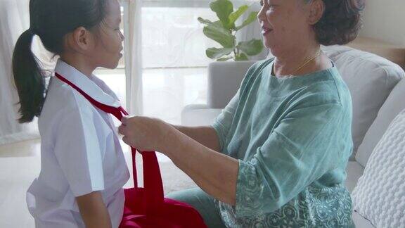 亚洲奶奶帮她的孙女打领带穿衣服准备去上学