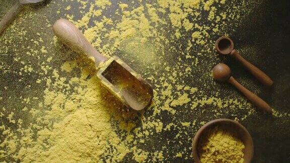 姜黄粉用木勺和勺子将干姜黄倒在黑色的桌子上
