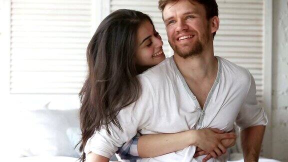 一对年轻夫妇坐在床上漂亮的女人拥抱着男人