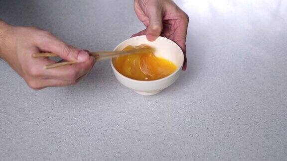 用筷子在淡黄色的碗中搅拌鸡蛋的慢动作模式