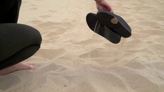 慢镜头中凉鞋被捡起来沙滩上的沙子被抖掉