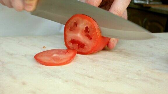 厨师用手切一个鲜红的番茄