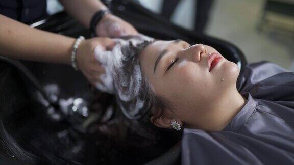 亚洲华人女性躺在美发沙龙洗头眼睛闭着
