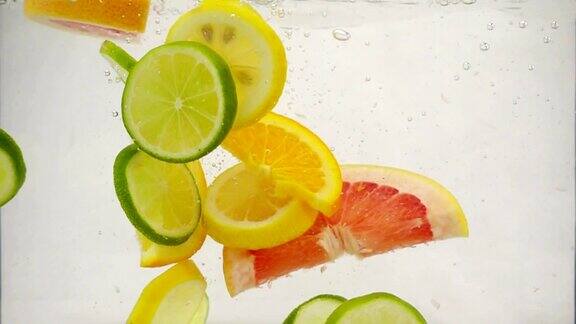 几片柠檬、柠檬、橙子、葡萄柚等柑橘类水果落入水中溅起水花和气泡这是慢镜头特写