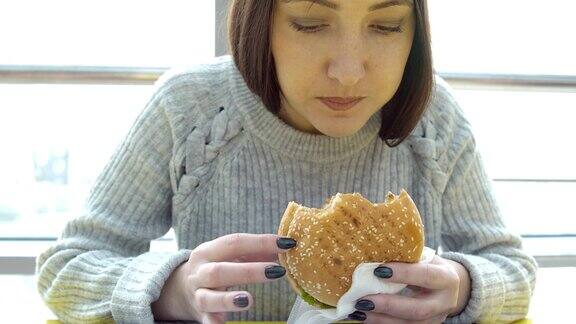 年轻女子吃了一个汉堡有害的脂肪的食物