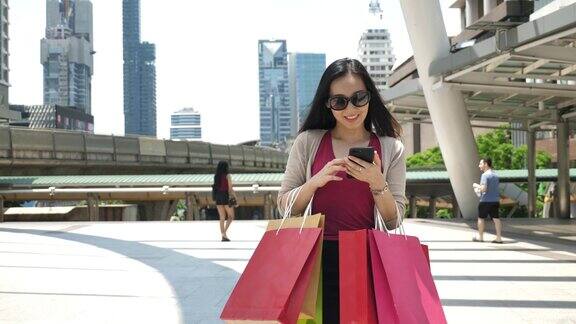 女人用购物袋购物后使用智能手机