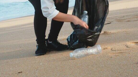 给一个年轻女人打扫卫生在沙滩上捡垃圾