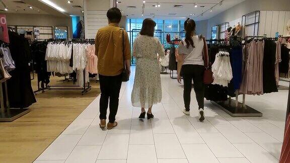 3个亚裔华人女性朋友带着购物袋和口罩在服装店买衣服