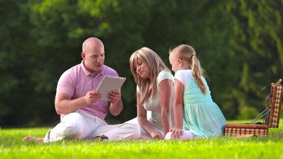 HDDOLLY:年轻的家庭在公园使用数字平板电脑