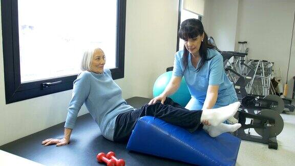 护士协助老年妇女进行腿部运动