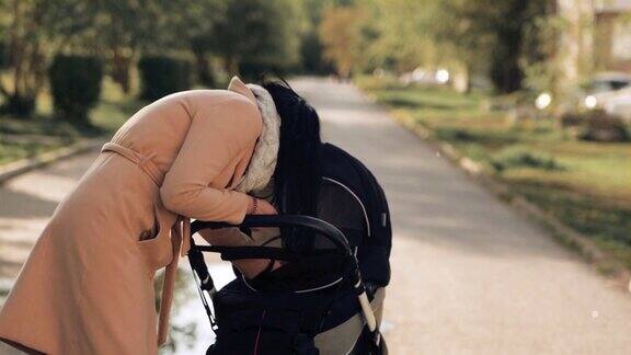 一个小女孩推着婴儿车在公园里走着一边讲电话