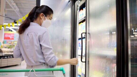 亚洲女孩戴口罩保护她的脸在超市购物