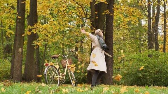一个年轻女子在秋天的公园里玩扔落叶