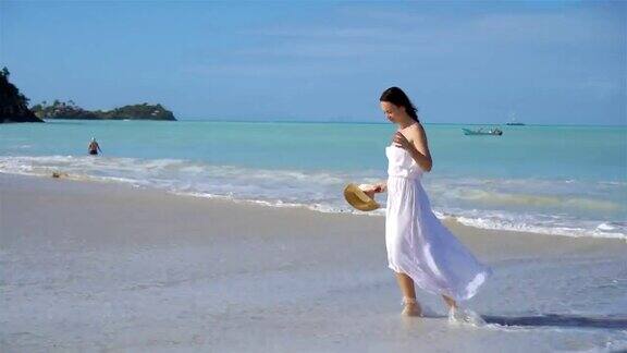 年轻美丽的女人在白色的热带沙滩上