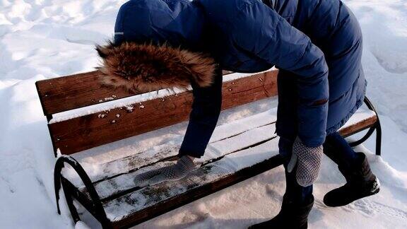 冬季城市公园里一名妇女正在清理长凳上的积雪