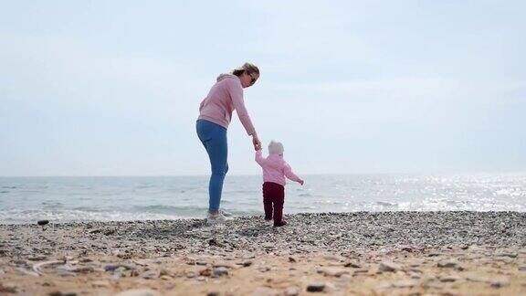 一位母亲牵着孩子的手向大海走去户外散步实时