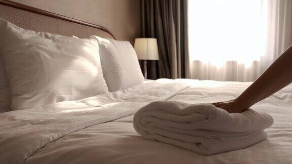 一个女人在床单上放了一条新毛巾房间服务