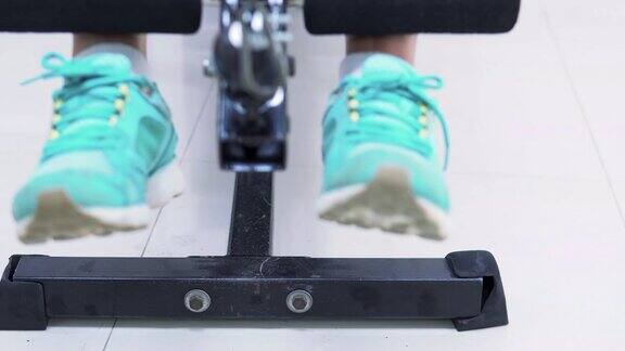 在体育馆里用力量锻炼机锻炼肌肉的年轻健身女性的近距离双腿