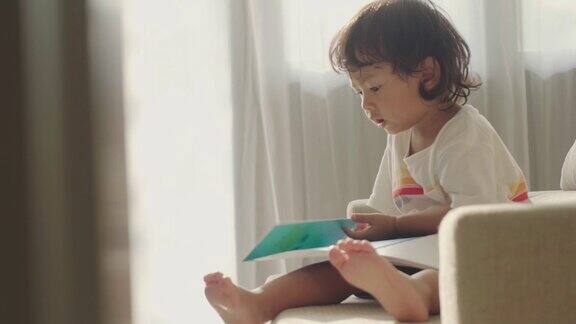 亚洲小男孩在沙发上看书
