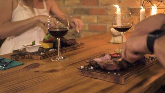 男人和女人切牛排而晚餐蜡烛在晚上餐厅浪漫的情侣在烧烤餐厅用餐