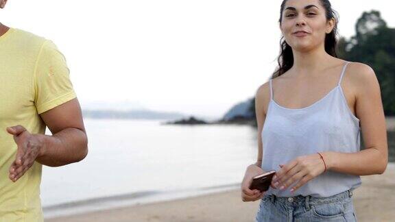 人们在海滩上聊天手持手机青年游客群体交流