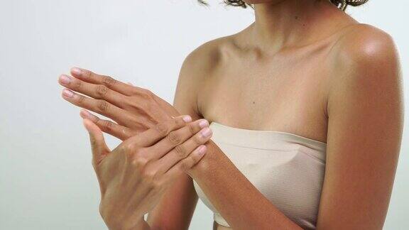 特写非洲妇女的手摩擦皮肤与美丽的护肤产品在白色的背景