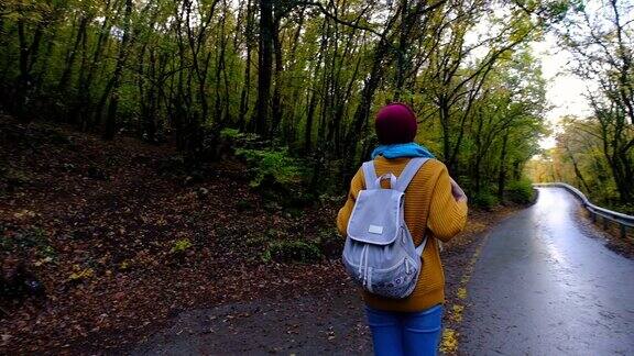 年轻女子休息后散步在森林里背着一个背包在日落光在秋天的季节森林