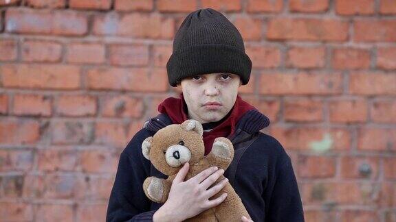 无家可归的男孩抱着一只泰迪熊