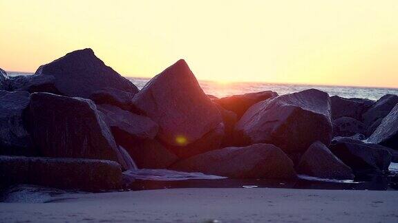 日落时分在威尼斯海滩的岩石上溅起浪花