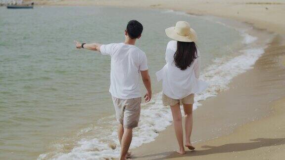 亚洲夫妇在海边散步玩耍享受假期的夏天愉快地谈笑看海滩上的景色