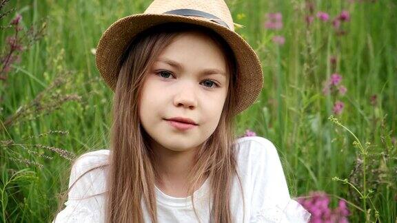 小女孩戴着帽子坐在草地上捧着鲜花孩子笑了靠近一点