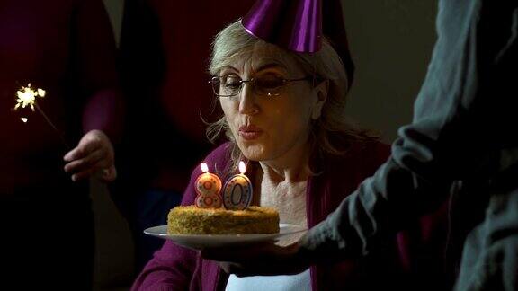 老妇人吹灭蛋糕上的蜡烛微笑着庆祝80大寿