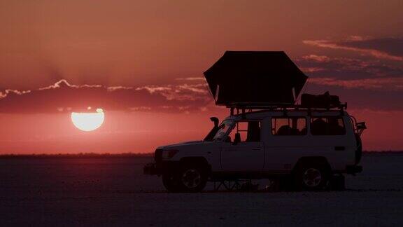 在Makgadikgadipan博茨瓦纳一辆4x4旅游车辆的延时拍摄和日落