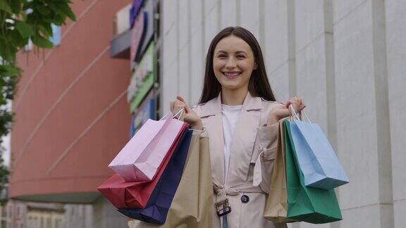 快乐的女人拿着袋子站在购物中心附近