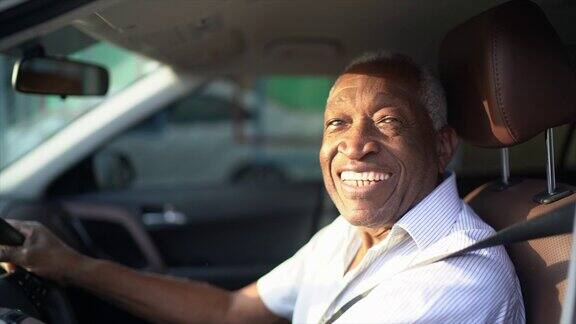 微笑的老人开着车看着镜头