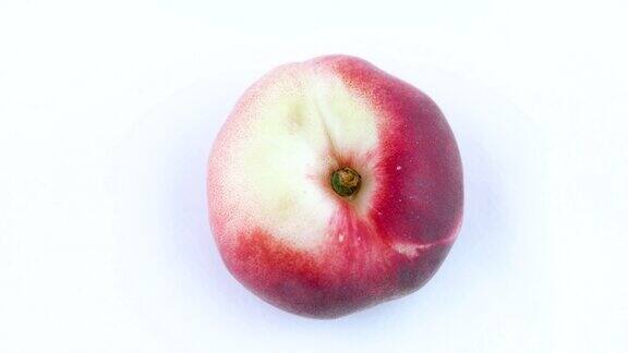 一个扁平的桃子在转盘上旋转孤立在白色背景上特写镜头宏