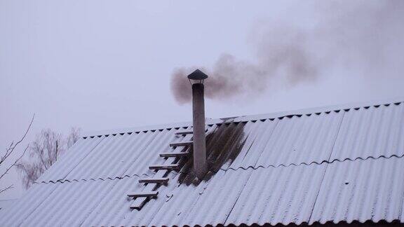 冬天火炉的烟从澡堂屋顶的烟囱里冒出来背景是晴朗的天空屋顶被雪覆盖着一缕缕烟从烟囱里冒出来