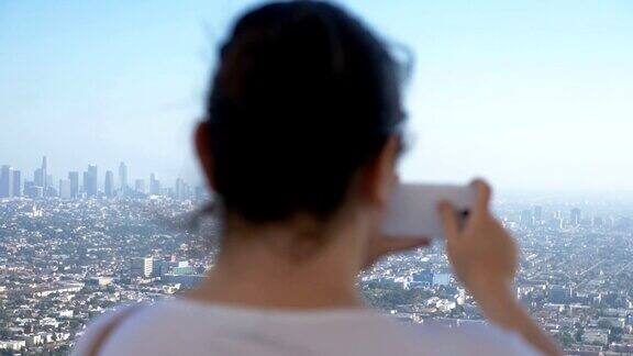 一个女人在拍摄洛杉矶市中心的照片4k慢镜头每秒60帧