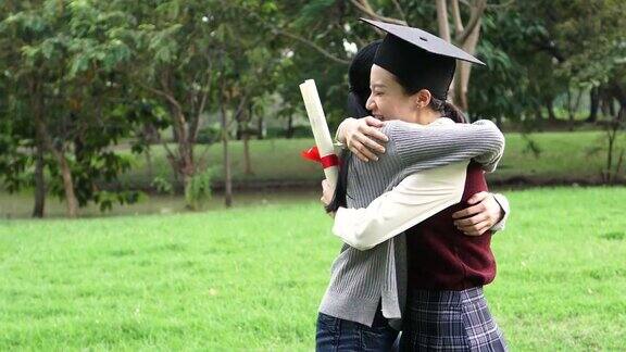 年轻的亚洲女毕业生在毕业典礼上拥抱她的朋友国际多元化背景