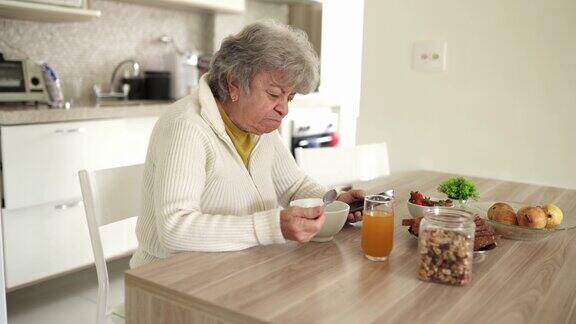 老年女性在吃早餐时使用智能手机