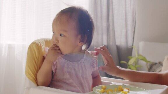 亚洲女婴在高喂养椅上进食