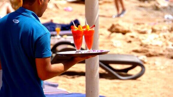 侍者在埃及海滩上斟酒侍者端着一个盛着热带果汁的托盘