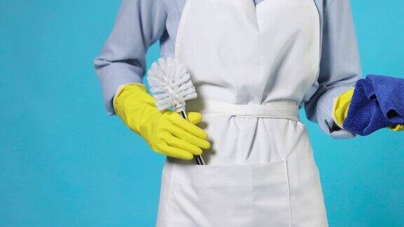 专业清洁妇女在黄色橡胶手套和清洁围裙拿抹布和马桶刷
