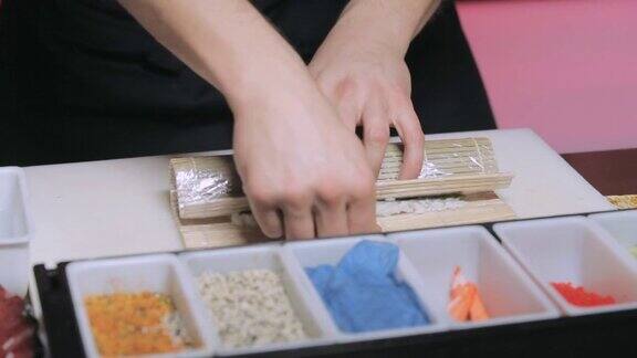 厨师的手在餐具垫上卷寿司把寿司卷里外包起来