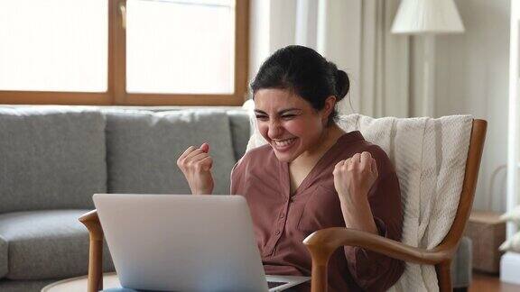 印度妇女看着笔记本电脑感到高兴庆祝好消息