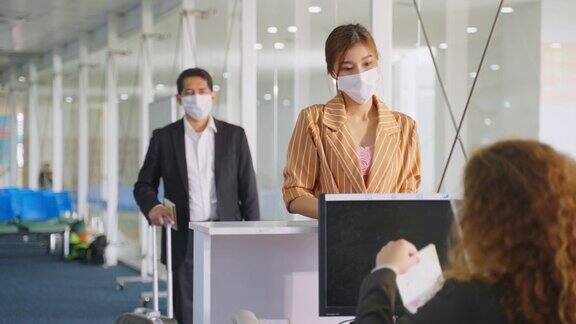 亚洲女性旅客将护照交给航空公司值机柜台的女工作人员以便签发机票登机牌女孩戴口罩预防冠状病毒大流行新常态的生活方式