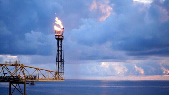 慢动作的气体火炬燃烧在海上的油气平台上在海与蓝天为油气行业